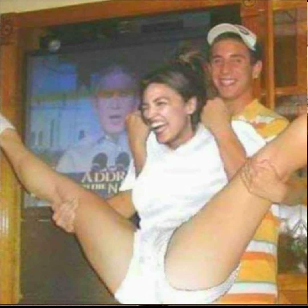 AOC legs spread at a party